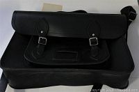 Front view of the large black leather messenger bag showing the front flap and two buckle straps and the front pocket.