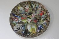 Full view of the round vintage metal wall plate with abstract multicolor enameled design.
