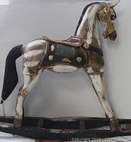 Side profile of the painted wooden rocking horse showing its detailed saddle and body painting.