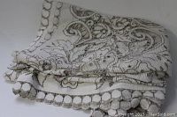 Folded tablecloth showing lace scalloped edges and dense lace pattern in cream and beige tones.