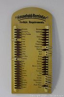 Photo of a yellow vintage metal household reminder list with sliding markers to indicate grocery items needed, listing various pantry staples and household products.