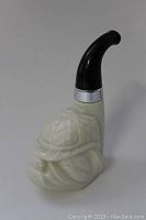 Clear image of a white vintage Avon bottle shaped like a bulldog wearing a hat with a black pipe stem and silver band at approx 6 inches tall.