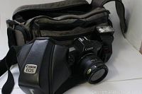 Canon EOS 650 film camera with black leather protective case, olive green carrying bag in background