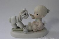 Side view of Precious Moments figurine showing child painting zebra toy horse