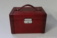 Closed view of red folding jewelry case showing textured exterior, handle and metal lock