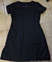 Full view of navy blue Pink Tartan dress laid flat to show short sleeves, fitted waist and overall shape.