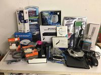 Wide view showing all items arranged including boxed MP3/CD player, DVD player, cordless cutter, phone and messaging system, adapters