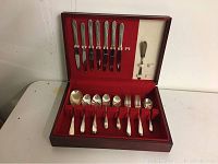 Full view of silverware set inside the wooden box with red velvet lining showing knives on the lid and other utensils in the base.