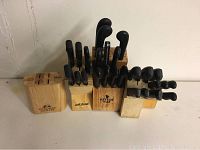 Front view of four wooden knife blocks with black handled knives inserted, arranged side by side
