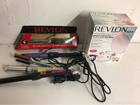 Several Revlon curling irons and wands shown tangled with power cords alongside the boxed Revlon Spa manicure and pedicure system.