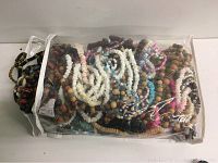 Plastic bag containing multiple costume jewelry strands made of wood beads, chip beads, and painted beads in various colors