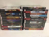 Photo showing 31 PlayStation 2 games stacked in two piles with visible spine titles.