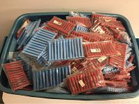 Top view of large blue plastic storage bin filled with packaged blue and red plastic perm rods, mainly red 2 inch and blue 3 inch sizes.