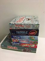 Stack of board games including Pictureka, Dabble, Disney Pop-Up Game, Candy Land, UNO, and Risk