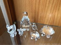 Photo shows all six figurines arranged on a glass shelf including adult and baby fox, penguin, and turtle.