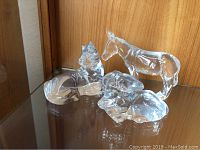 All three figurines displayed together on glass shelf, front view