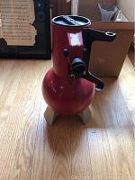 Front view of red Edmund Scientific reflector telescope with angled eyepiece and beige tripod base.