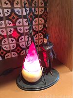Full display of the iron man figure and campfire lamp lit with red light on a wooden surface with patterned background.