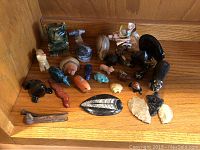 Wide view of collection showing carved stone spirit animal figurines, arrowheads, and antique nails arranged on a wooden shelf.