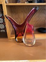 Two signed art glass vases displayed together on a shelf showing color and form.