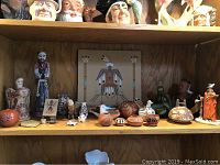 Shelf displaying Native American Southwestern collectibles including pottery, figurines, and paintings