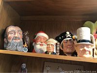 Shelf display of 5 Royal Doulton character head mugs including Merlin, Long John Silver, Santa Claus, Native American Chief, and Gentleman with Top Hat.