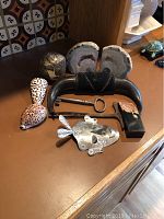 All items arranged on a brown surface showing geodes, ram horn bookends, large key, shells, metallic lizard and iron object