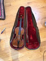 Violin and bow inside open zippered case showing overall fit and red velvet interior