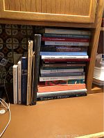 Stack of approximately 25 art books on a counter, titles visible include Norman Rockwell, Becoming van Gogh, Impressionism, Picasso drawings.