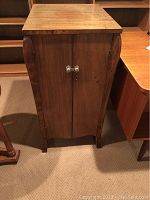 Front view of wooden record cabinet with two doors, curved sides, and flat top.