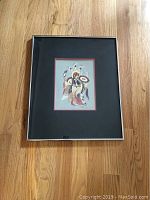 Framed silk screen print on hardwood floor, showing overall presentation with frame and matting.