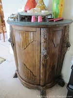 Left side front angle of the wooden ornate bar showing lion head door handle and curved panels.