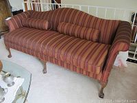 Full view of large sofa with striped upholstery and wooden legs.