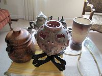 Wide view of lot on glass table showing all items including coffee pots, vases and ceramic pot.