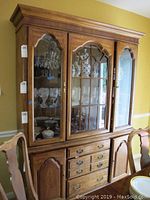 Large wooden china cabinet with glass display doors, drawers, and lower storage cabinets shown front and side view.