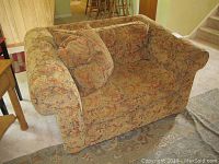 Front and side view of oversized armchair showing patterned upholstery and wear on arms.