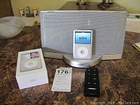 Overview showing Bose speaker dock, Apple iPod Classic docked, iPod box and IR remote