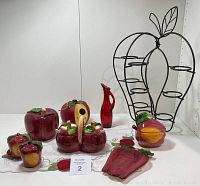 Set of apple-themed ceramic kitchen items with metal apple-shaped rack on a white surface