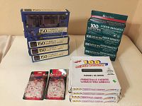 Photo showing multiple boxes of Christmas light strings including 3 boxes of 150 multi-colored swing style lights, 5 boxes of 100 super bright white lights with green wire, and 2 packages of red string lights with clear bulbs on a plain surface.