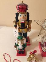 Photo of two decorative nutcracker figurines, one large with a red sequined crown and one small with a green crown, both on red bases.