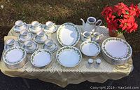 Full set of Crown Ming fine china with holly pattern arranged on table outdoors, showing all pieces.