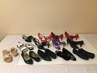 Overview of 12 pairs of women's footwear in size 7 arranged on white background, showing a variety of styles including heels, flats, sandals, and wedges in multiple colors and materials.