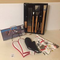 Photo of entire barbecue tool set including utensils, spice grinder, oven mitts, and kitchen towel.