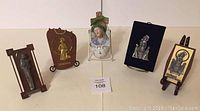 Full view of five religious-themed wall plaques and figurines arranged on a table