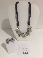 Photo shows the full set: a mother of pearl leaf bib necklace with black braided cord and matching leaf-shaped earrings on white stands.