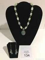 Photo shows necklace displayed on black bust with matching dangling earrings on a smaller stand, along with auction lot number card.