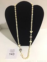 Full view of the mother of pearl bead necklace displayed on a black bust.