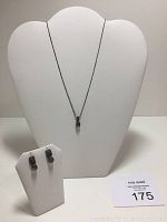 Full view of necklace on display stand with matching earrings on a smaller display stand alongside seller lot card.