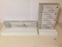 Photo shows five shelves in their original boxes stacked on the right, two unboxed white shelves of different sizes placed on the table, and one long white shelf lying flat on the table.