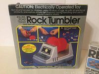 Photo showing the box of the electrically operated Rolling Stones Rock Tumbler toy with images of the device and usage instructions on the box.